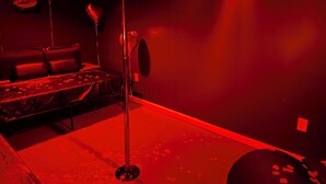 Une pièce faiblement éclairée, avec un lit, un lampadaire et un luminaire fixé au mur.