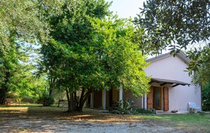 A house with a porch, surrounded by trees and a gravel path.