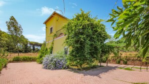 A yellow building with a brick pathway leading to it, surrounded by greenery and trees. - Awesome home in Roma with WiFi (Roma)