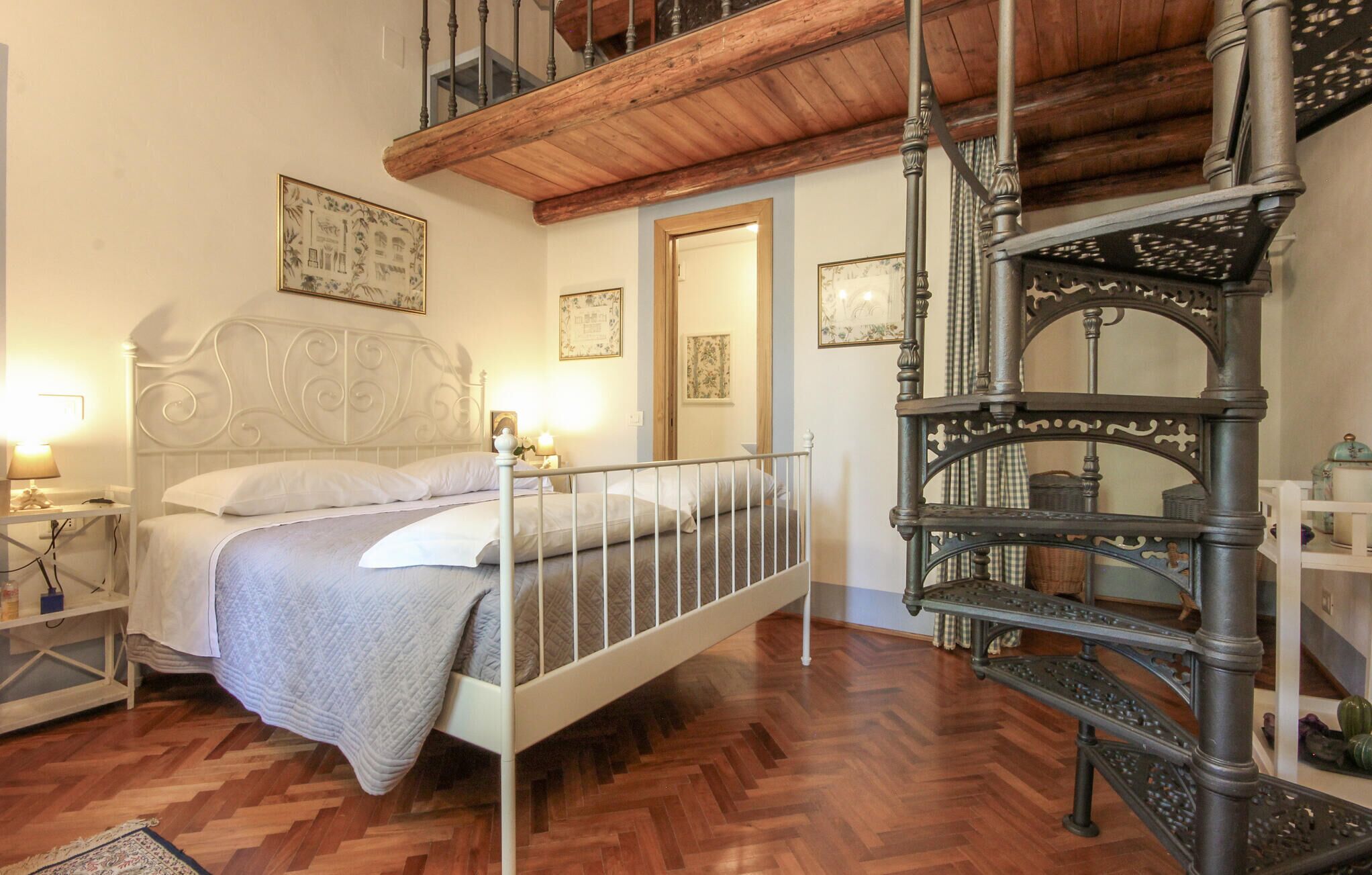 Ein Schlafzimmer mit einem Bett, Holzboden, einer Treppe und Wandbildern.
