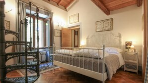 A bedroom with a four-poster bed, a wooden staircase, and a chandelier. - Gorgeous home in Roma (Roma)