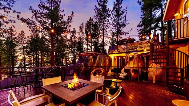 Eine Terrasse im Freien mit Feuerstelle, Holzdeck und Stühlen.