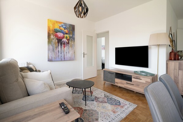 Ein Wohnzimmer mit einer Couch, einem Couchtisch, einem Fernseher und einem Bild an der Wand.