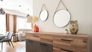Un salon moderne avec un meuble en bois, deux miroirs ronds et un vase accroché au mur.