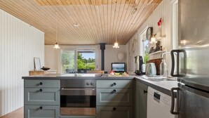 A modern kitchen with a central island, built-in oven, and stainless steel appliances.