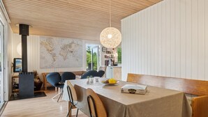 A dining area with a wooden table, chairs, and a hanging light fixture.