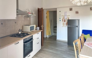 A compact kitchen with a stove, microwave, oven, and refrigerator.