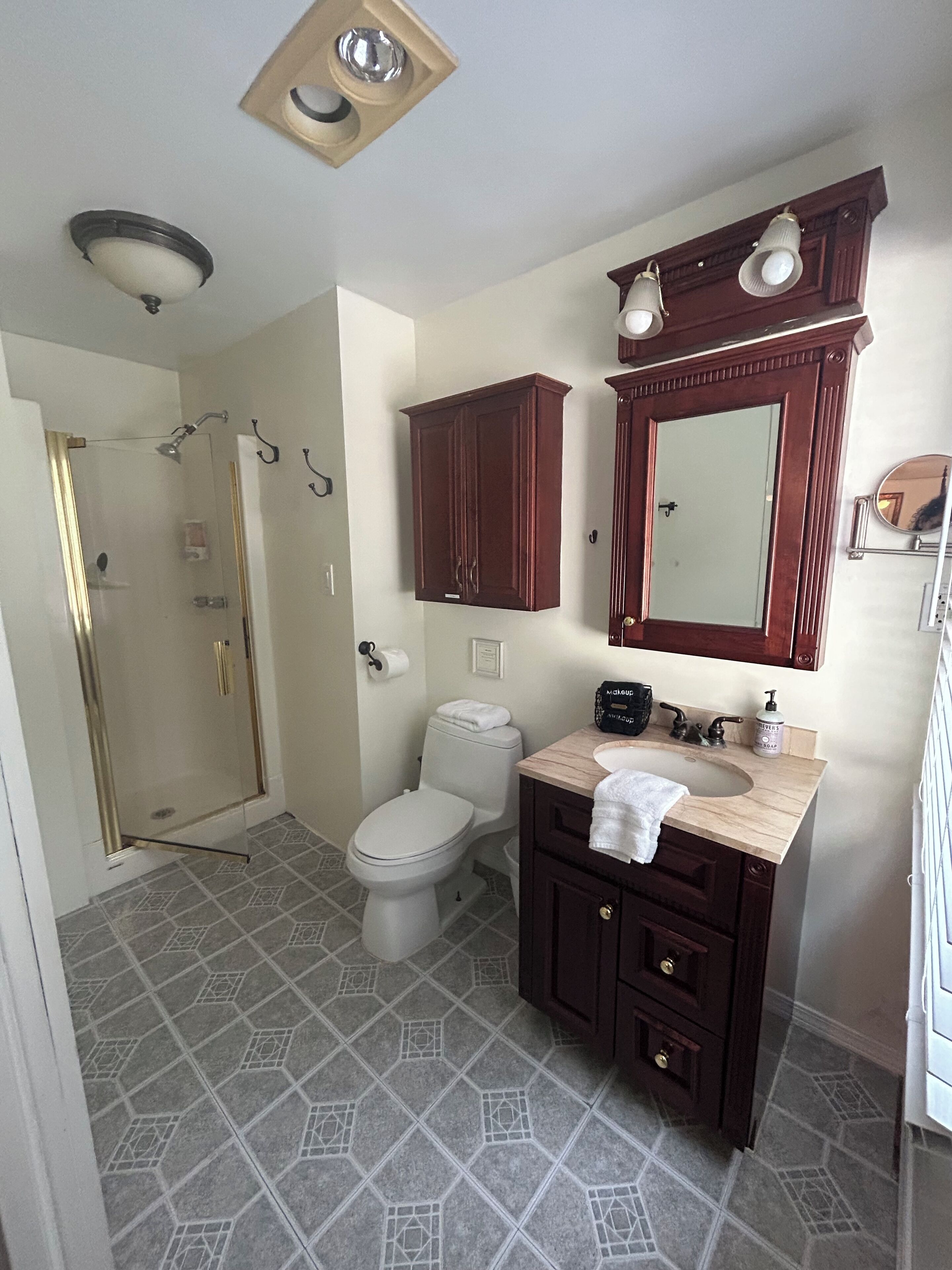 A bathroom with a toilet, a sink, a mirror, and a shower.