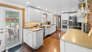 Una cocina moderna con armarios blancos, encimera de madera y electrodomésticos de acero inoxidable.