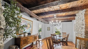 Un comedor con mobiliario de madera, una araña y una pared de piedra.
