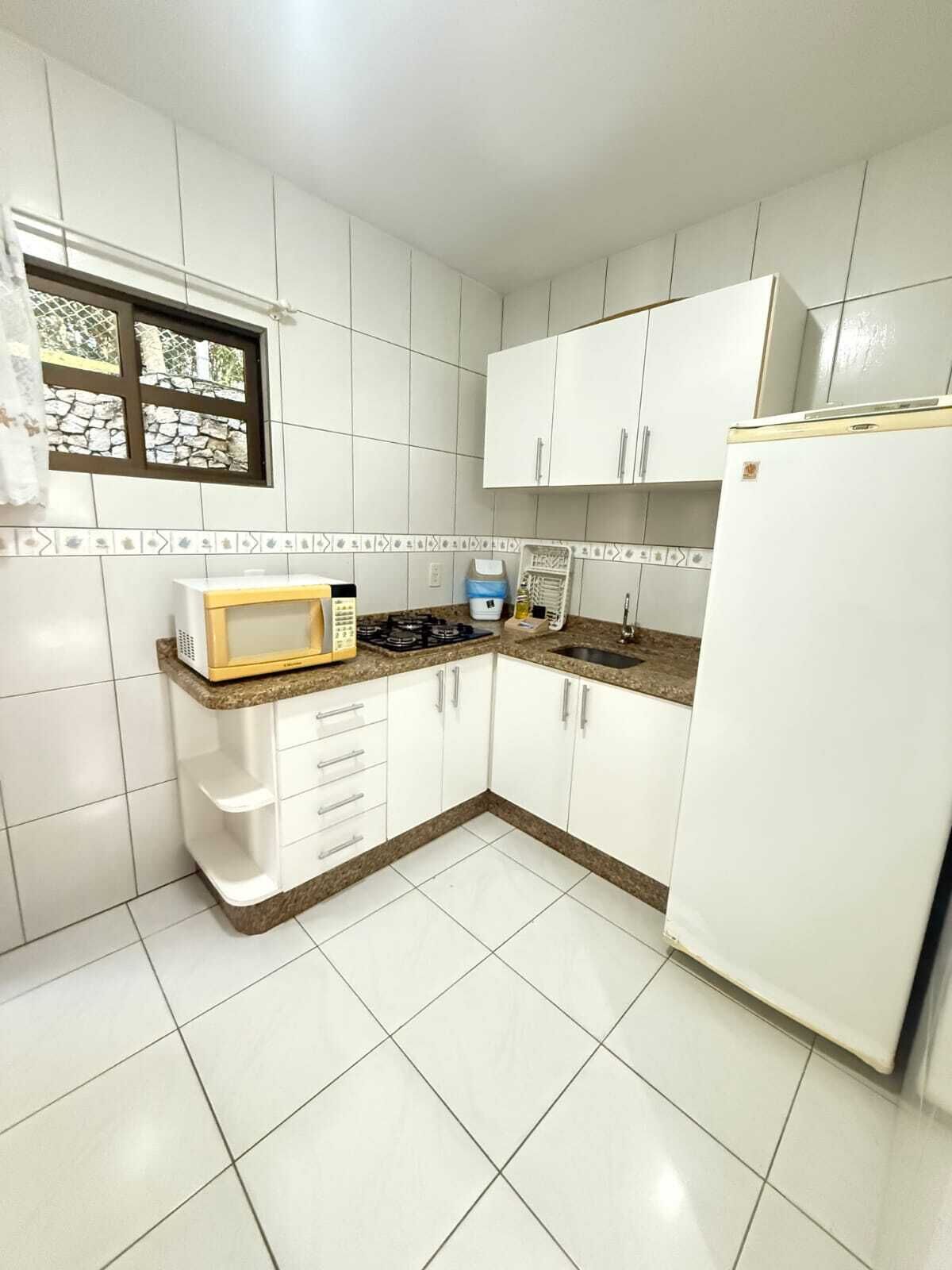 A compact kitchen with white cabinets, a microwave, a stove, and a refrigerator.