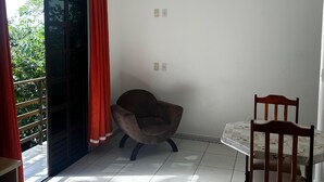 A room with a bed, a chair, a table, and a window with curtains.