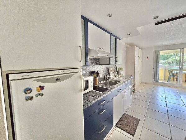 A kitchen with a refrigerator, microwave, and sink.