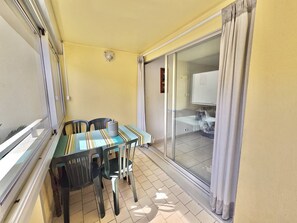 Ein Balkon mit Tisch und Stühlen, eine Schiebetür zu einem Badezimmer und eine gelbe Wand.