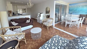 A modern living room with a sofa, chairs, a dining table, and a kitchen area. - CAP D'AGDE - Plage du Môle / Réf 405 (CAP D'AGDE)