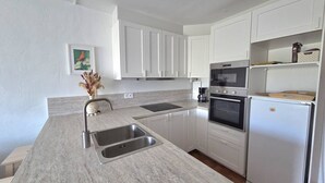 A modern kitchen with white cabinets, a double sink, an oven, and a refrigerator. - CAP D'AGDE - Plage du Môle / Réf 405 (CAP D'AGDE)