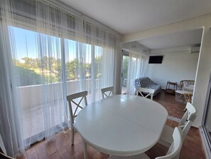 Una habitación con una mesa redonda y sillas, un sofá y un televisor en la pared.