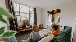 A living room with a green sofa, a television, and a child watching TV.