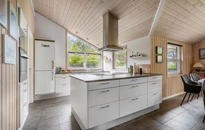 Une cuisine moderne dotée d’un îlot central, de meubles blancs et de poutres en bois au plafond.