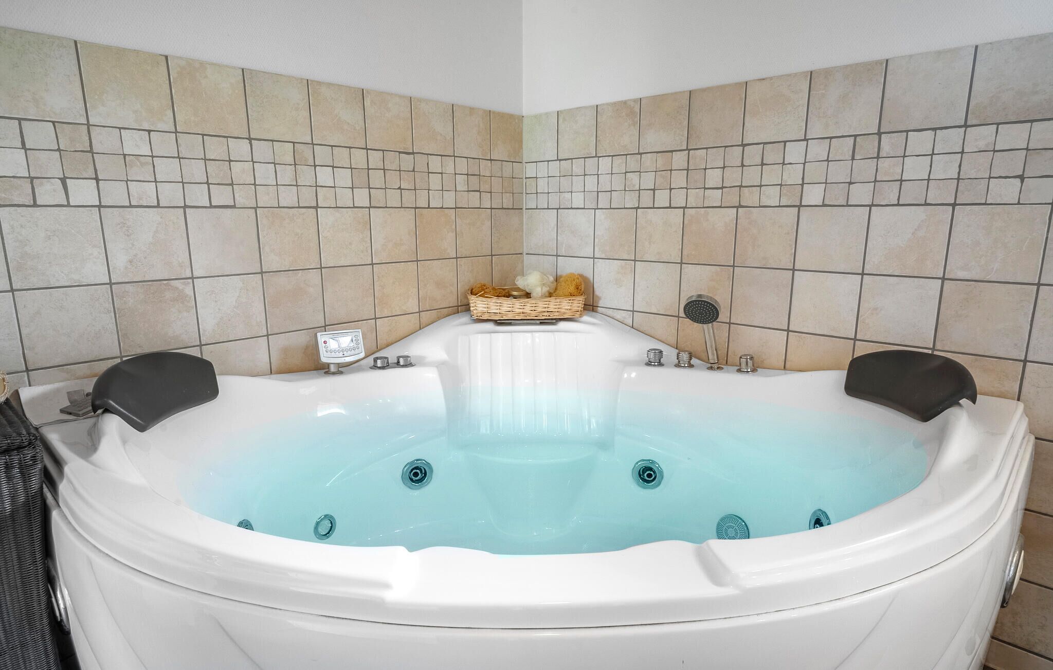A bathroom with a large bathtub, tiled walls, and a control panel.