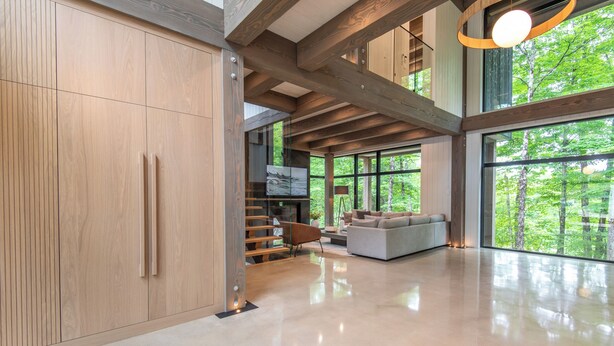 Un amplio salón con un gran ventanal, una escalera y una decoración de diseño moderno.