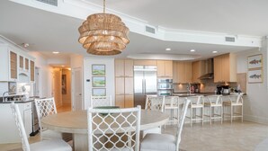 A modern kitchen with white cabinetry, a central island with seating, and a hanging light fixture.