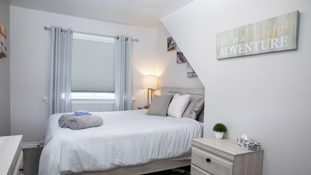 A neatly arranged bedroom with a bed, bedside table, lamp, and a motivational quote on the wall. - Cozy Bancroft Stay in the Minnow Lake area (Greater Sudbury)