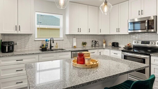 A modern kitchen with white cabinets, a granite countertop, a built-in microwave, and a stainless steel oven. - 3 bedroom, 2 bath house, sleeps 6+, baby bed W (Hood County)