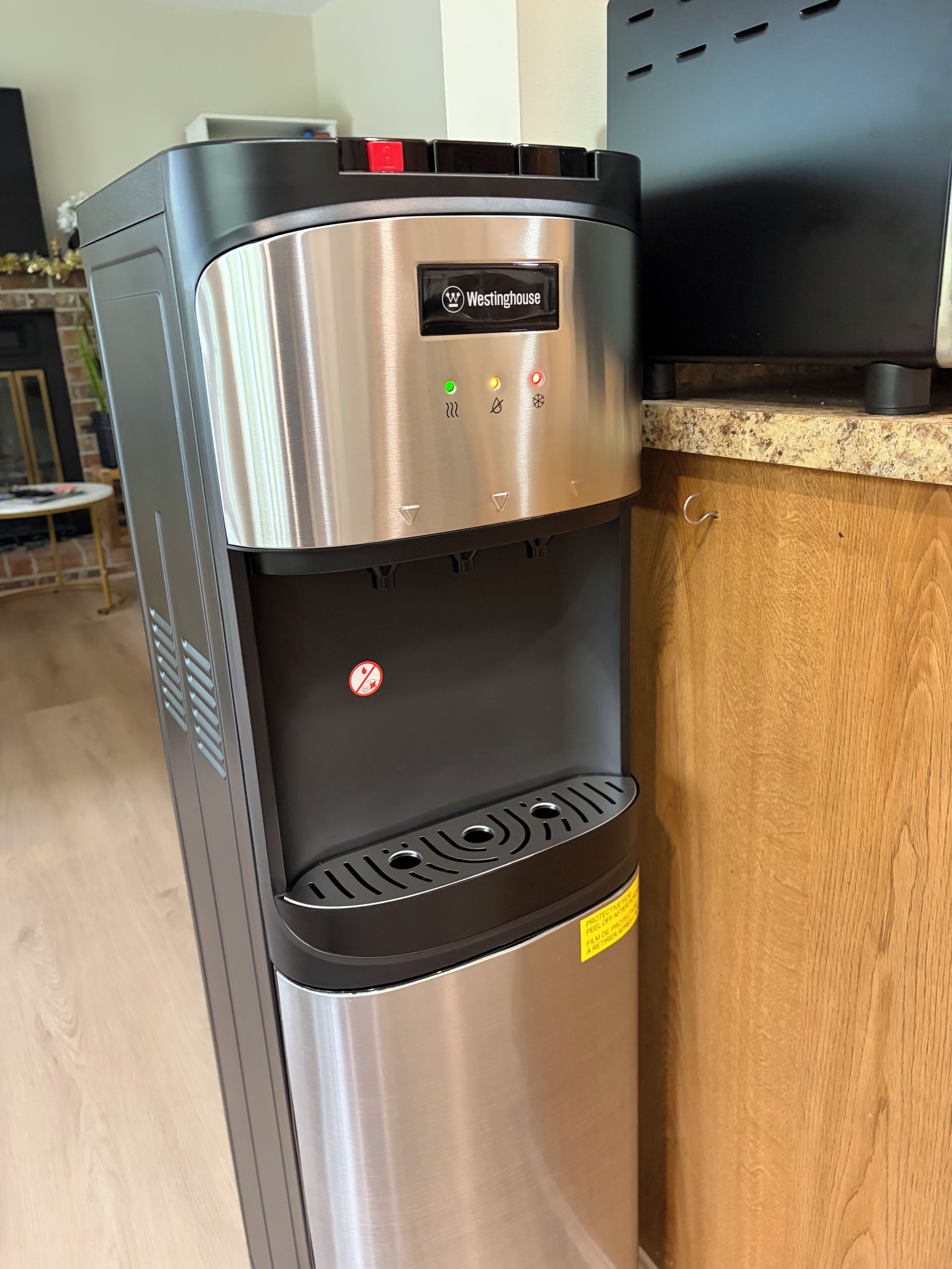 A stainless steel water dispenser with a Westinghouse logo, a control panel with various buttons, and a warning label.