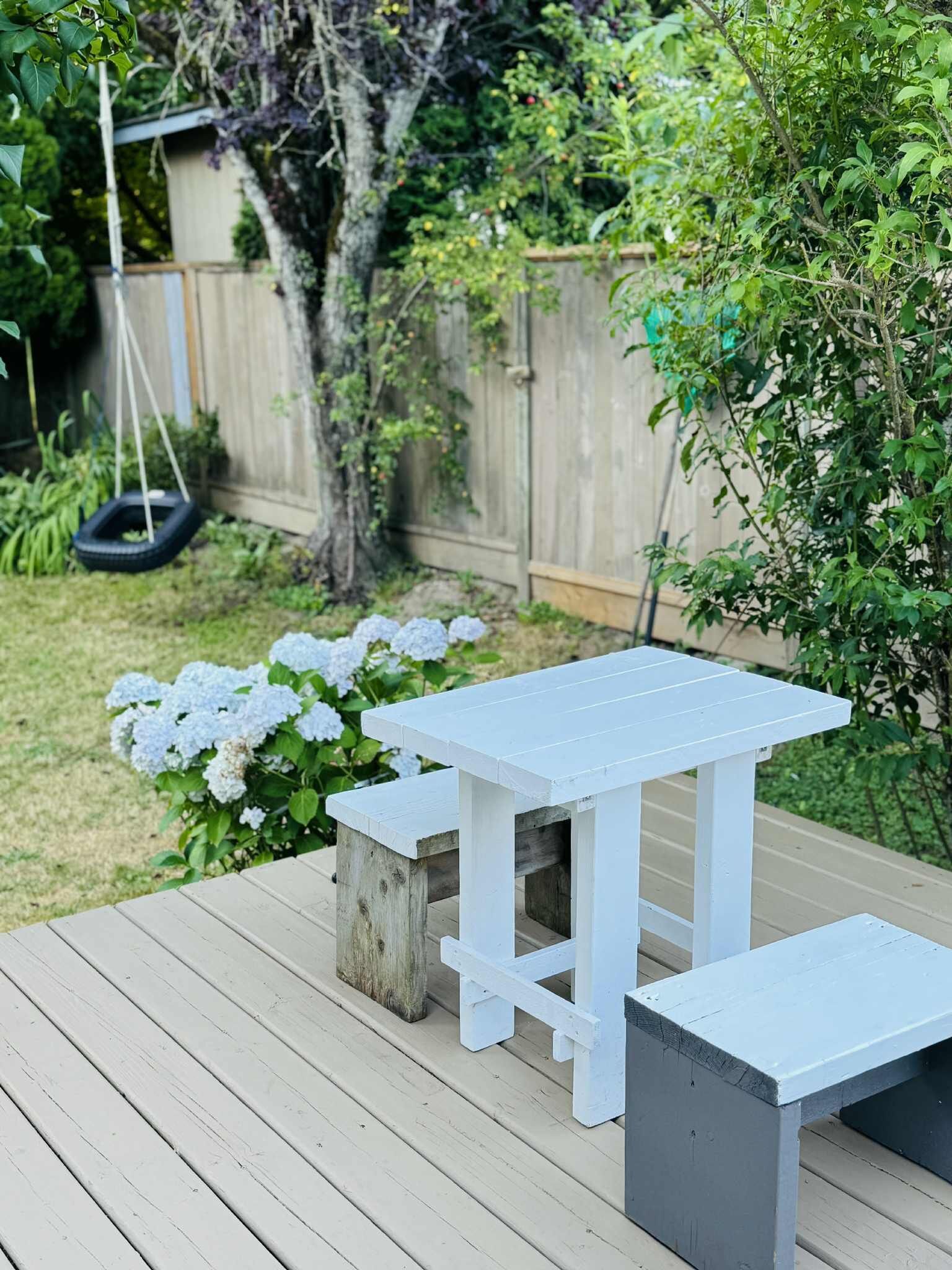A wooden deck with a white table and benches.