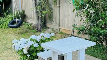 A wooden deck with a white table and benches.