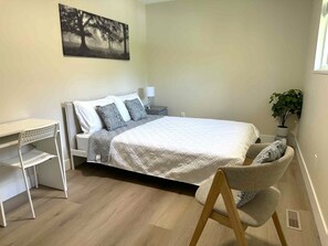 A bedroom with a bed, a desk, a chair, a nightstand, and a wall-mounted plant. - Fabulous 1-bedroom in Surrey, British Columbia, Canada (Surrey)
