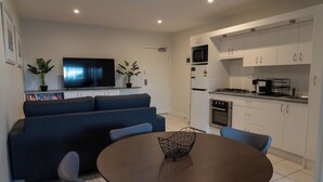 A modern living room with a sofa, TV, and dining area. - Charming 2 Apartments in delightful Islington with AC, Balcony & Wifi. (Islington)