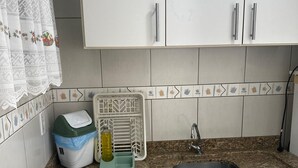 Una cocina con armarios blancos, encimera de granito, pileta de acero inoxidable, cocina a gas y escurreplatos.