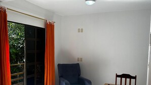 Una habitación con un sillón azul, una mesa de comedor de madera y un tapete estampado.