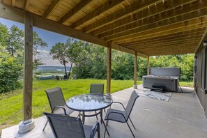 Un patio al aire libre con una mesa redonda y sillas, una parrilla y vistas a un área verde con árboles y un paisaje lejano.