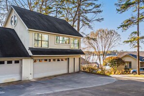 Ett tvåvåningshus med garage, en uppfart och utsikt över en sjö eller annat vattendrag.