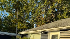 Ein Wohnhaus mit Terrasse, Sitzgelegenheiten im Freien und einem Grill.