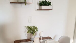 Ein Esstisch mit zwei Stühlen, einem Blumentopf und einem an der Wand befestigten Regal mit einer Pflanze.