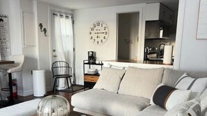 A modern living room with a sectional sofa, a coffee table, and a dining area with a kitchen in the background. - Lakefront Getaway Sparrow Lake Muskoka Beach House (Gravenhurst)