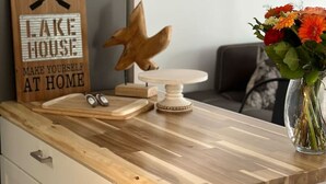 A kitchen counter with a wooden sign that reads "WELCOME TO OUR LAKE HOUSE MAKE YOURSELF AT HOME," a decorative bird, and a vase with flowers. - Lakefront Getaway Sparrow Lake Muskoka Beach House (Gravenhurst)