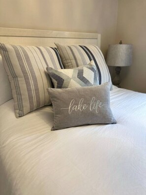 Ein Bett mit gestreiften Kissen und einem Kissen mit der Aufschrift "lake life".