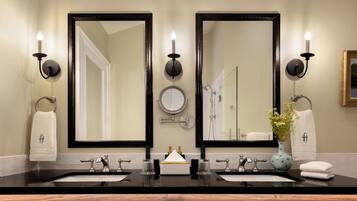 Baño con dos lavamanos, dos espejos y un florero con flores.