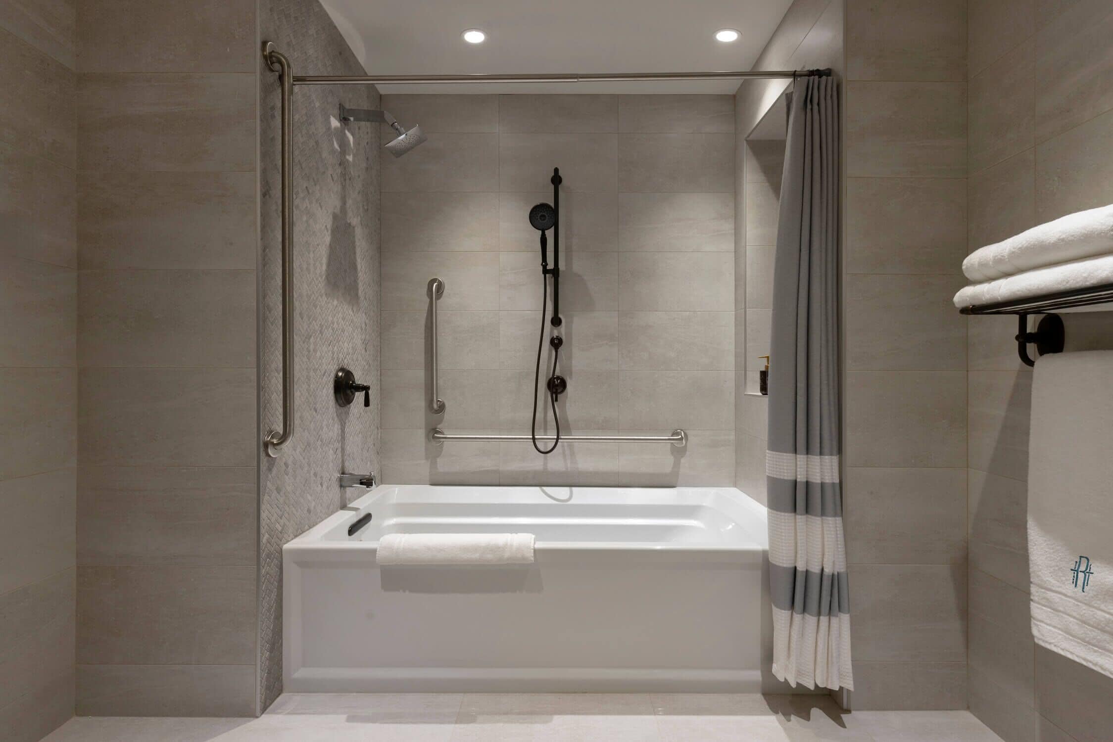 Un baño moderno con ducha de vidrio, una bañera blanca y un perchero para toallas.