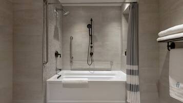 Un baño moderno con ducha de vidrio, una bañera blanca y un perchero para toallas.