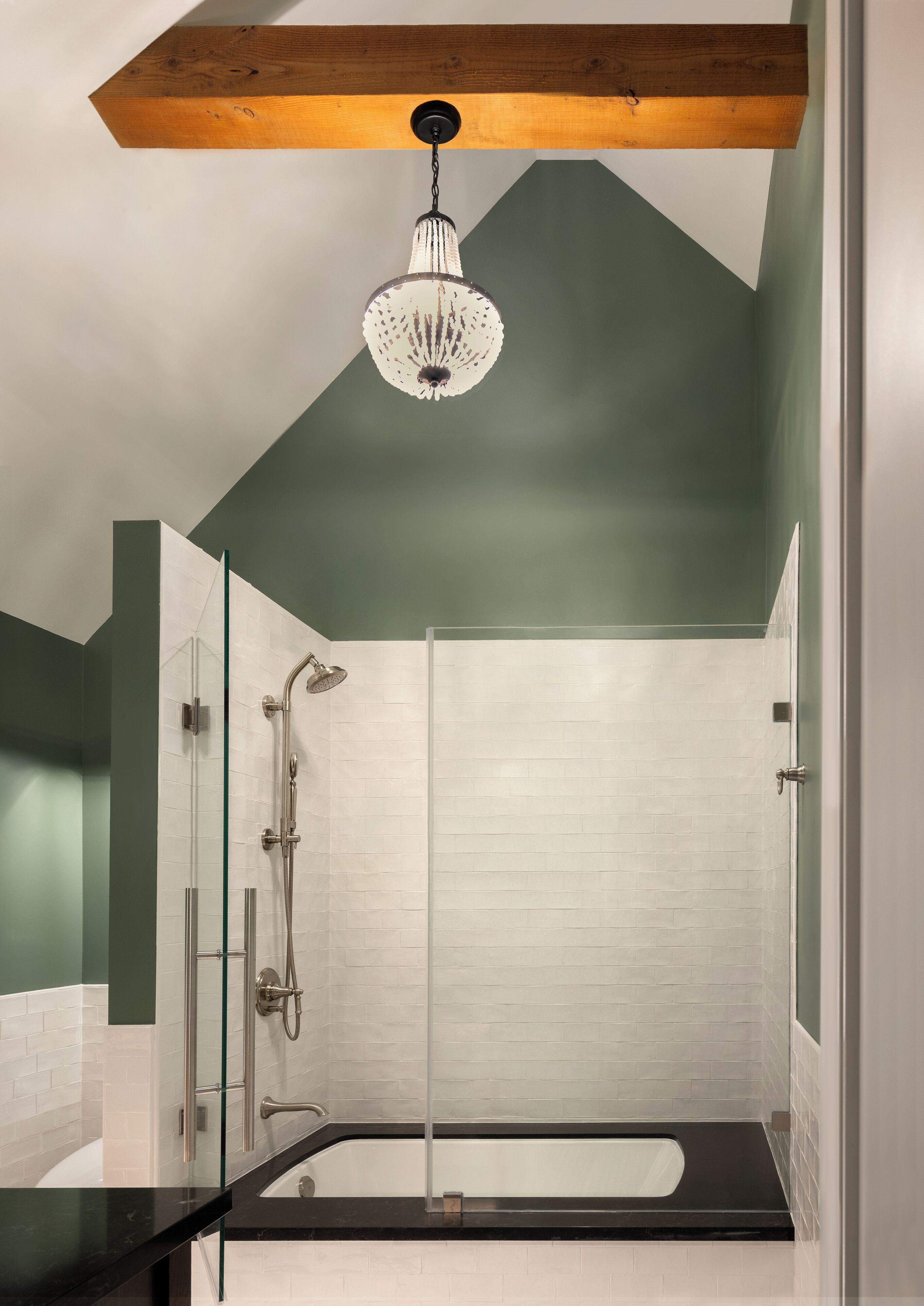 Un baño moderno con cabina de ducha de vidrio, encimera negra y viguela de madera en el techo.