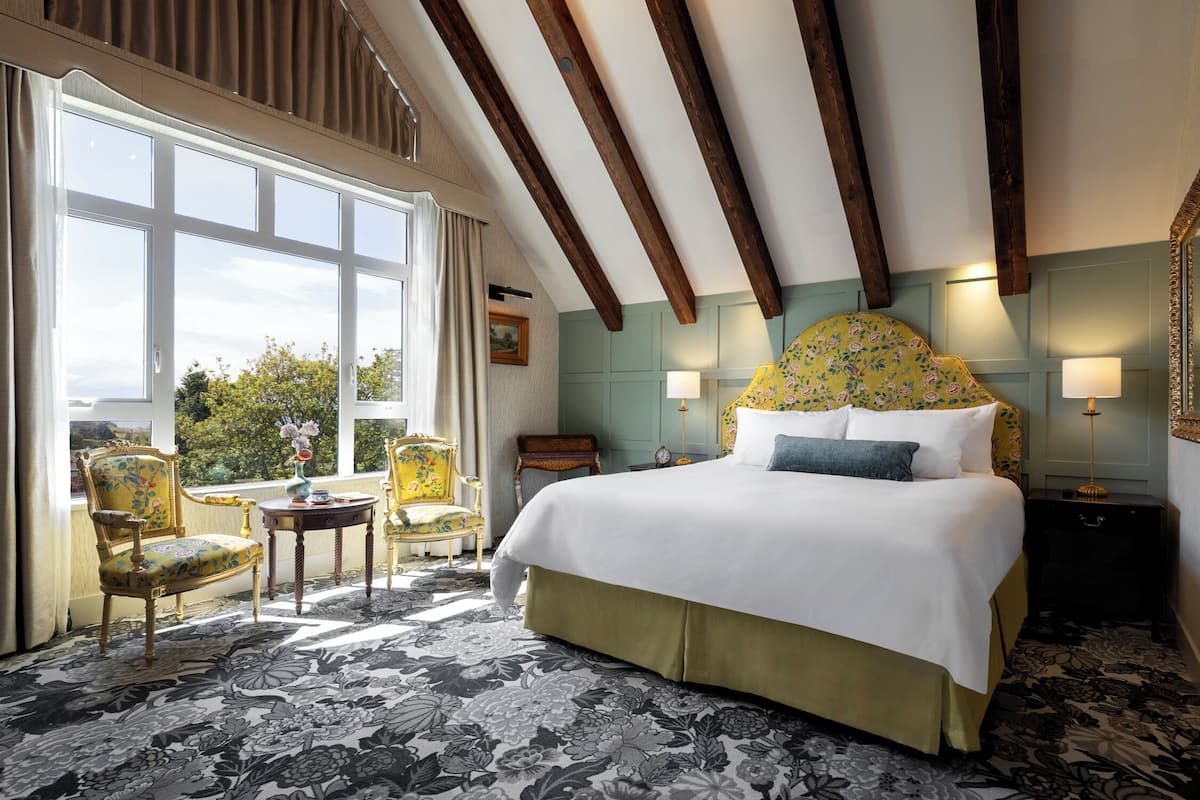 A bedroom with a large bed, a window, a chair, and a table.