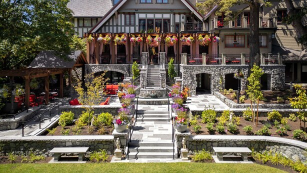 Ein großes, mehrgeschossiges Gebäude mit einer steinernen Fassade, einer zentralen Treppe und einem gepflegten Garten mit verschiedenen Pflanzen und Blumen.