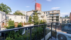 Un edificio de apartamentos moderno con balcones, una grúa de construcción al fondo y un cielo despejado.