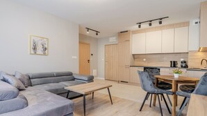 Una sala de estar moderna con un sofá seccional gris, una mesa de centro de madera y un comedor con una mesa de madera y sillas tapizadas en gris.